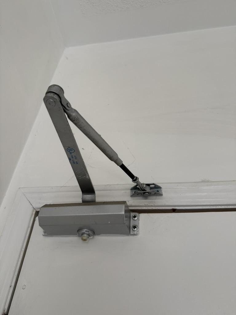 Surface-mounted door closer on a white door frame