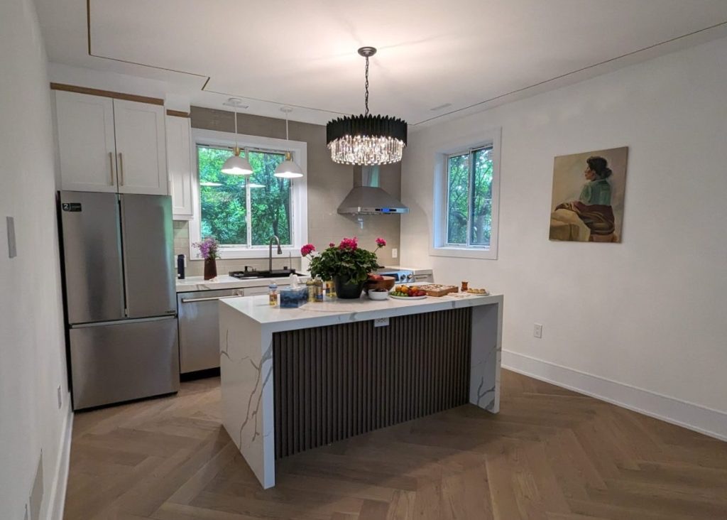 Kitchen with a white island and herringbone wood floor inside a backyard garden suite