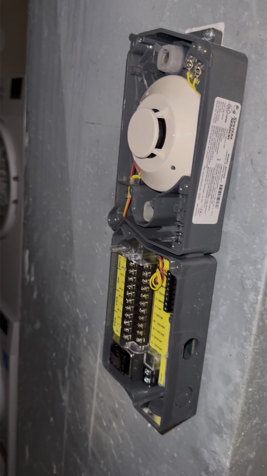 Duct smoke detector housing being wired on a basement wall
