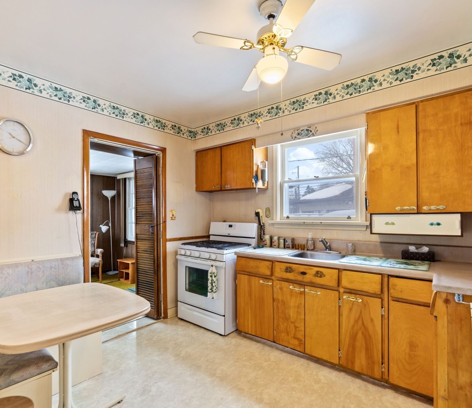 Dated kitchen with honey-toned wood cabinets, laminate counter and wallpaper border