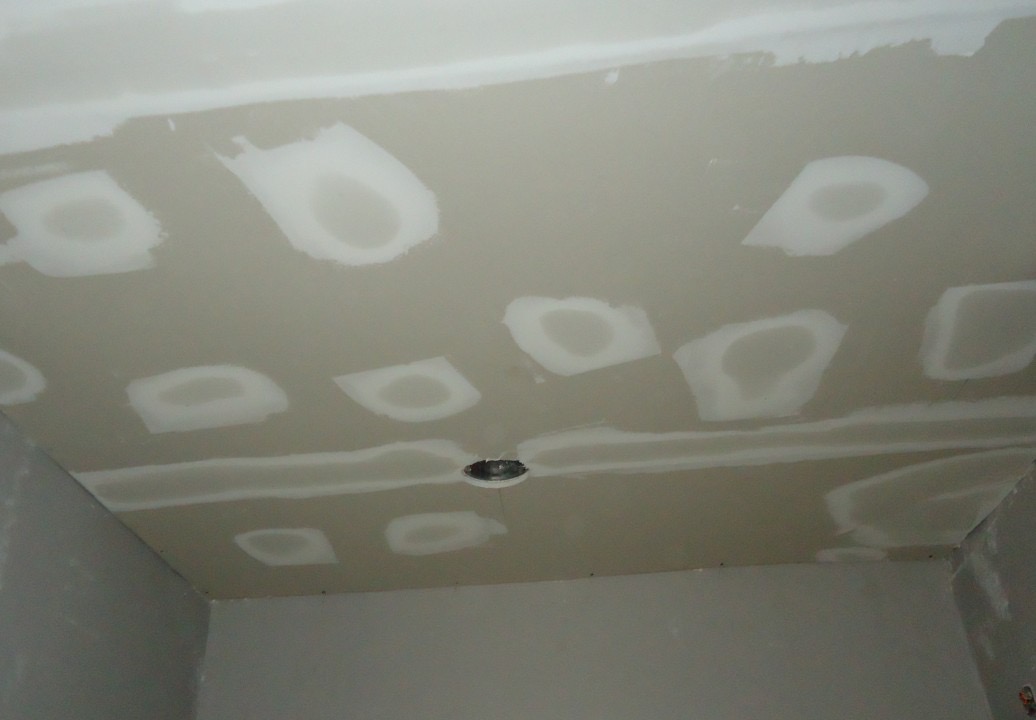 Ceiling with joint compound patches over screws and drywall seams, not yet sanded
