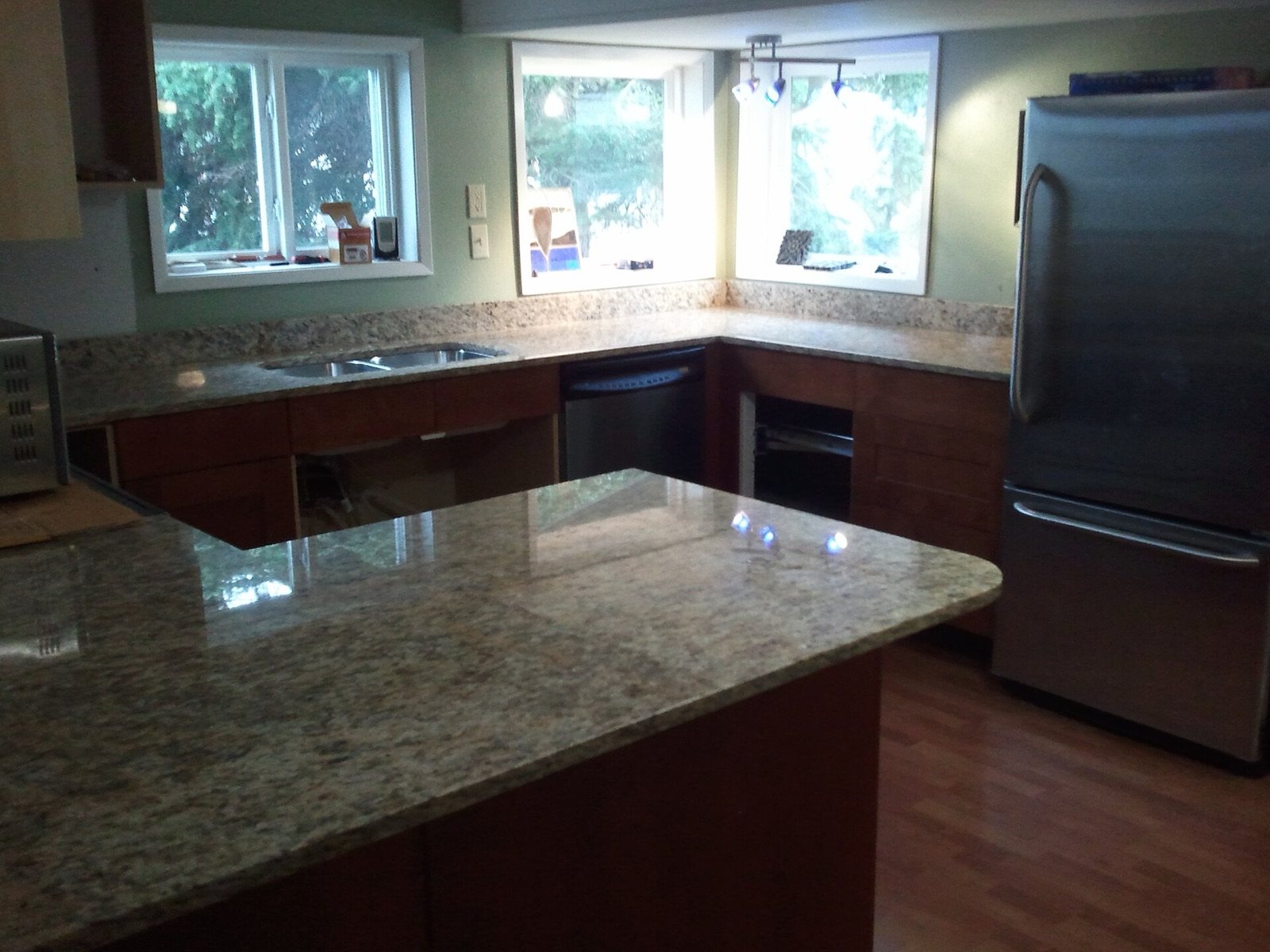 Kitchen with newly installed speckled granite countertops, an undermount sink and a curved peninsula