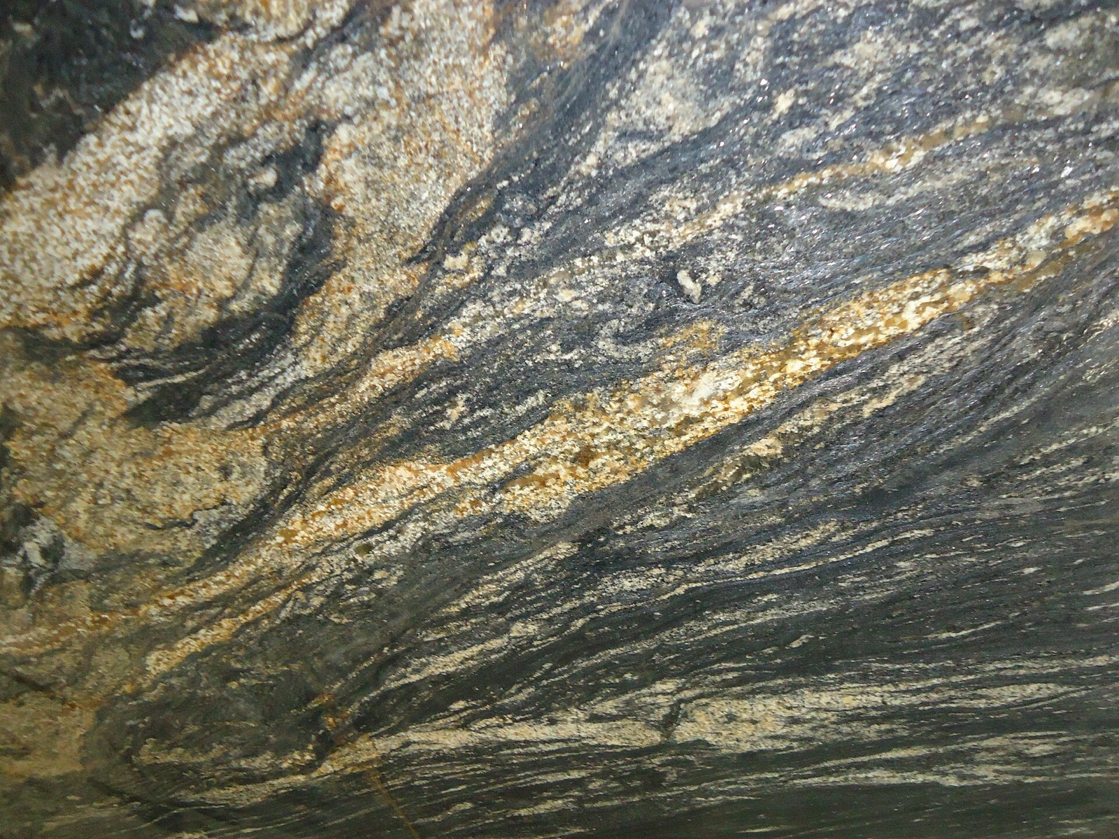 Close-up of a polished granite slab with dark grey and gold swirling bands