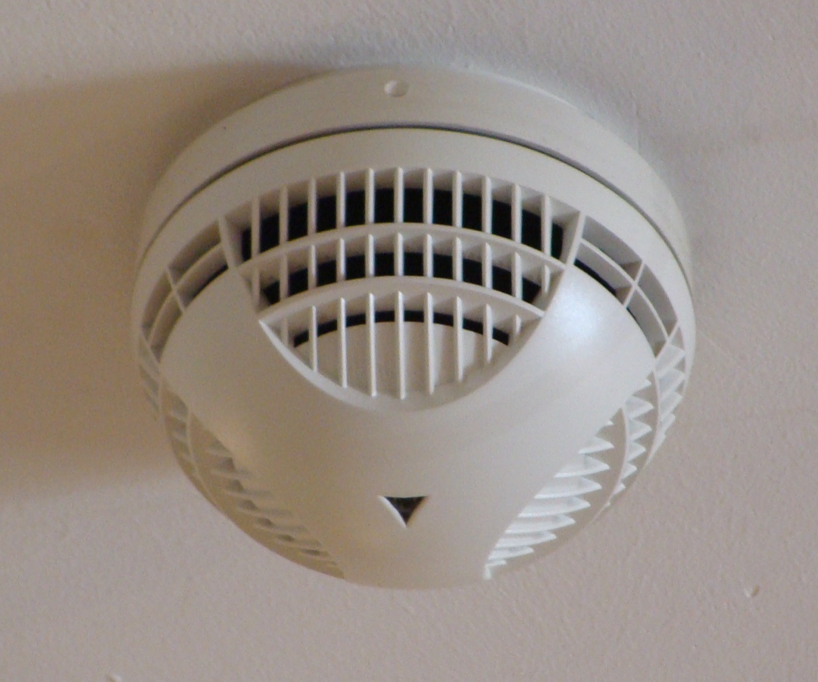 White smoke detector mounted on a ceiling