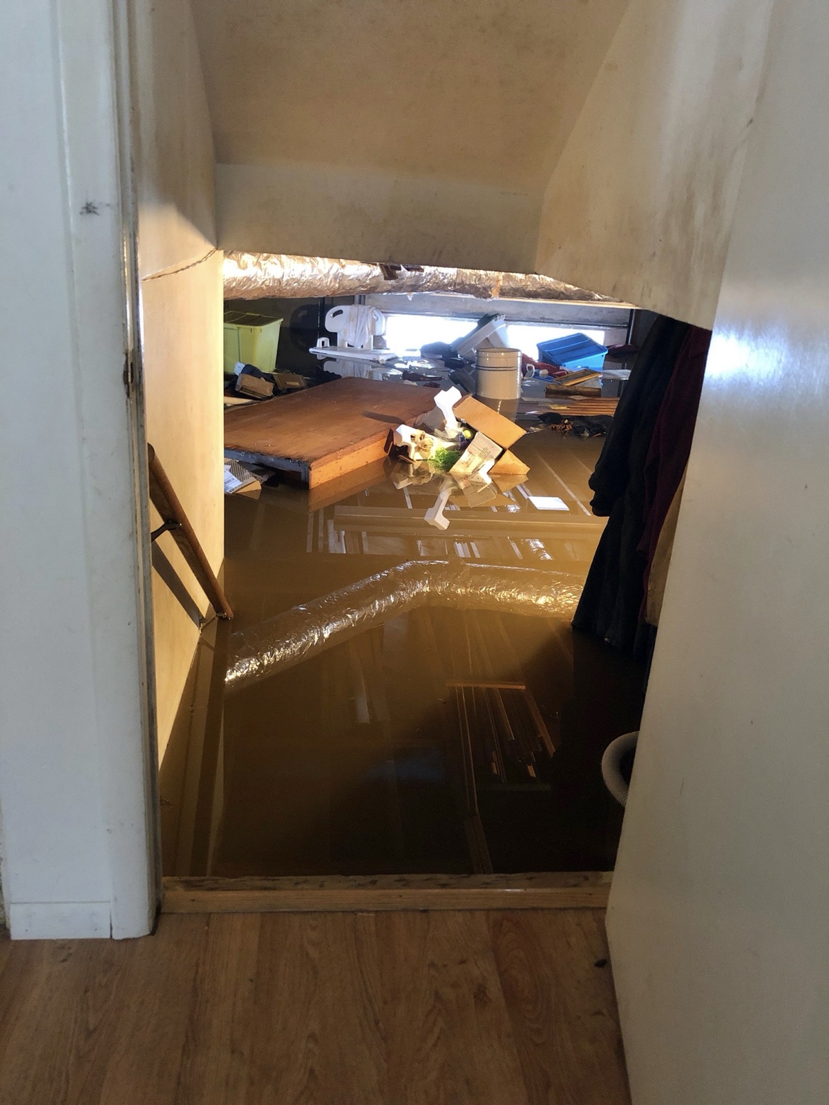 Basement flooded with brown water seen from the top of the stairs
