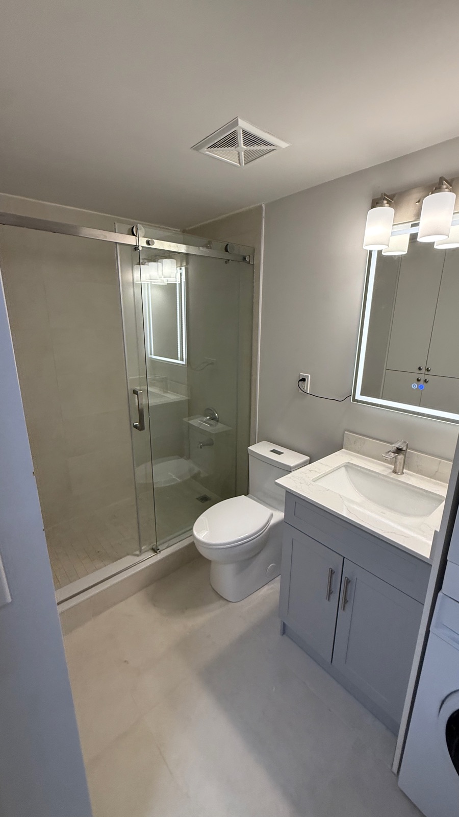 The same bathroom with a tiled walk-in shower and sliding glass doors