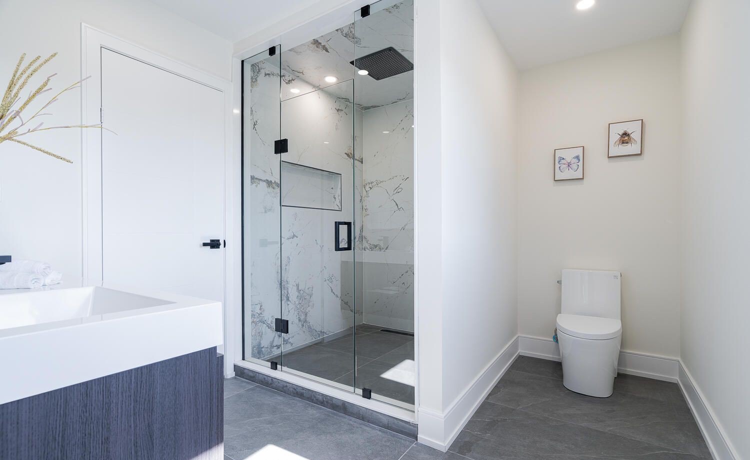 Tiled walk-in shower with frameless glass, a built-in niche and a linear drain