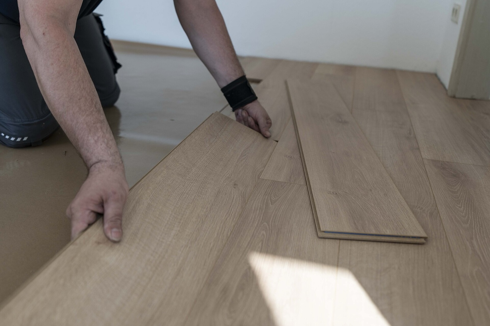 Installer clicking laminate planks together over an underlay sheet
